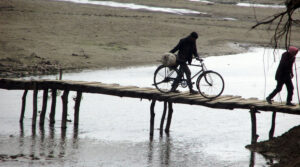 शुल्क तिरेर काठको पुल तर्दै स्थानीयवासी